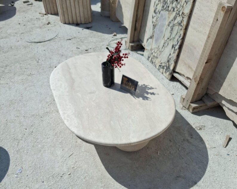 May include: A white oval-shaped coffee table with a smooth, polished surface. The table is made of natural stone and has a unique, organic shape.