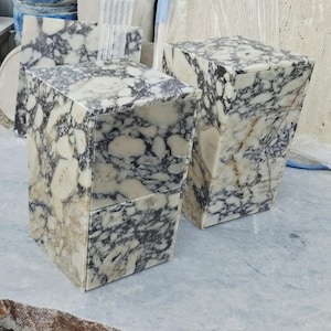 May include: Two rectangular side tables crafted from polished stone featuring a high-contrast pattern of large, irregular white and cream-colored patches interspersed with dark charcoal and black veining throughout the entire surface area.