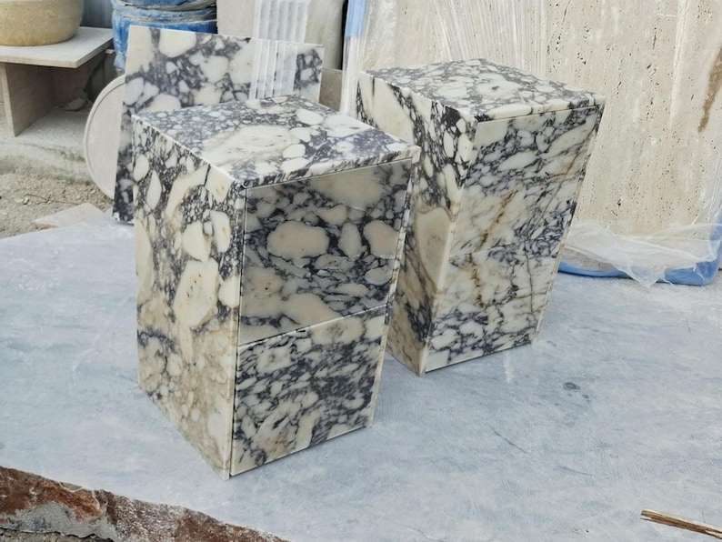 May include: Two rectangular side tables crafted from polished stone featuring a high-contrast pattern of large, irregular white and cream-colored patches interspersed with dark charcoal and black veining throughout the entire surface area.
