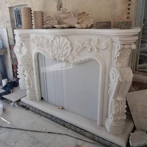 Chimenea de mármol de lujo con repisa de Carrara y Calacatta personalizada, hecha a mano en piedra natural para interiores modernos y clásicos.