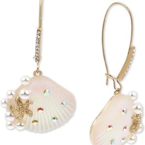 May include: A pair of gold-tone seashell earrings. Each earring features a pearlescent seashell design adorned with faux pearls, iridescent crystals, and a gold starfish accent. The earrings have a fish hook closure and a decorative crystal-studded bar.