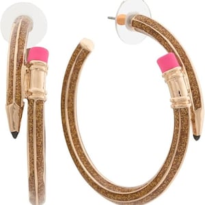 May include: Gold-toned hoop earrings shaped like pencils. The earrings have a glittery brown finish with a pink eraser and a black pencil tip. The earrings are designed to look like pencils.