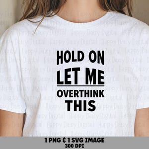 May include: A white short-sleeved t-shirt featuring bold black text centered on the chest that reads, "HOLD ON LET ME OVERTHINK THIS." The lettering is arranged in four lines with a horizontal line separating the second and third phrases.
