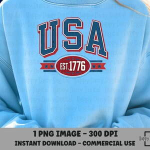 May include: Pale blue sweatshirt featuring a red, white, and blue "USA" design. The graphic includes "EST. 1776" in a red oval. The sweatshirt is a casual style, suitable for patriotic events. The image also includes the text "1 PNG IMAGE - 300 DPI INSTANT DOWNLOAD - COMMERCIAL USE".
