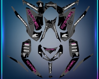 May include: A black and grey Yamaha Raptor 700 ATV graphic kit with pink accents. The kit includes graphics for the front, sides, and rear of the ATV. The graphics feature the words "Raptor" and "Yamaha" along with other logos and designs.