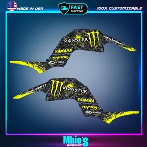May include: Two black and grey camouflage patterned vinyl decals for a vehicle, featuring bright yellow Monster Energy logos, Yamaha, Raptor, Renthal, and Pro Circuit text. The graphics have sharp, angular shapes with yellow splatter accents.