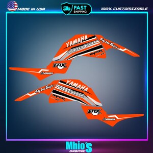 May include: Orange and white Yamaha Pro Circuit ATV graphics kit with Fox Racing and Troy Lee Designs logos.