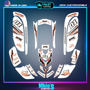 May include: A white and orange motorcycle graphic kit with the words "Pitster Pro", "Pro Circuit", "Fox", and "01" printed on it.