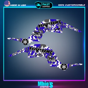 May include: A set of two blue, white, and gray camouflage graphic decals for a Yamaha Raptor ATV. The decals feature the words "RAPTOR" and "PRO CIRCUIT" in black lettering.