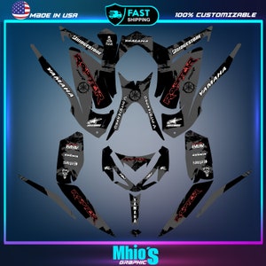 May include: A black and gray graphic design for a Yamaha Raptor 700 ATV. The design features the words "Raptor" and "Yamaha" in red, along with other sponsors and logos. The design is made for a dirt bike and has a grunge aesthetic.