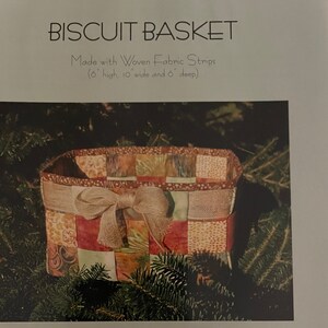 May include: A woven fabric biscuit basket with a brown ribbon bow. The basket is made with colorful fabric strips and measures 6 inches high, 10 inches wide, and 6 inches deep. The basket is made from Hoffman CA Fabrics Bali Pops.