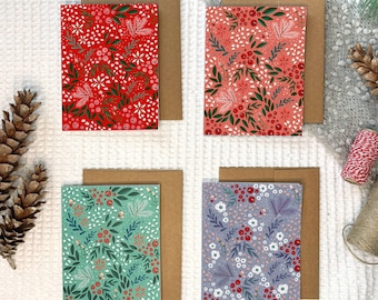May include: Four holiday greeting cards with different floral patterns. The cards are red, pink, green, and purple with white accents. Each card has a brown envelope.