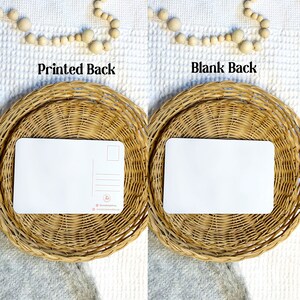 May include: Two blank postcards, one with a printed back and one with a blank back, are displayed on woven wicker coasters. The printed back features a small logo and website address.