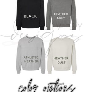 May include: Four crewneck sweatshirts in black, heather grey, athletic heather, and heather dust. Each sweatshirt has the colour name printed in white. The words "colour options" are written in cursive at the bottom.