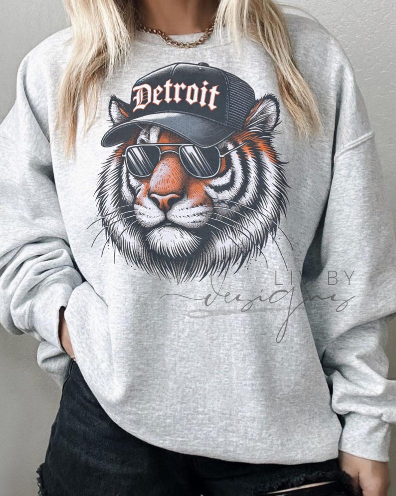 May include: Gray sweatshirt with a graphic of a tiger wearing sunglasses and a black baseball cap that says "Detroit".