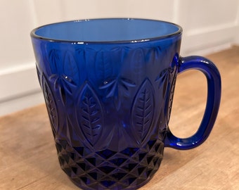 May include: A cobalt blue glass mug with a leaf pattern and a diamond-shaped pattern at the bottom.