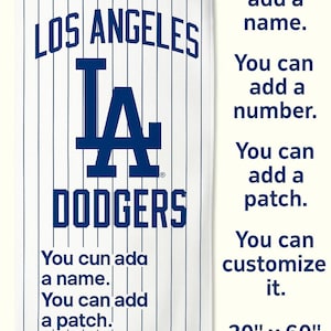 May include: A white and blue Los Angeles Dodgers beach towel with a baseball-themed design. The towel features the team's logo and the words "Los Angeles Dodgers". The towel is 30 inches by 60 inches.