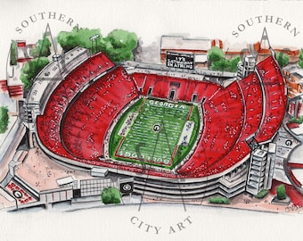 May include: Watercolor painting of a football stadium with red seating and a green field. The words "GEORGIA" and "BULLDOGS" are visible on the field. The text "IT'S SATURDAY IN ATHENS" is displayed above the stadium.