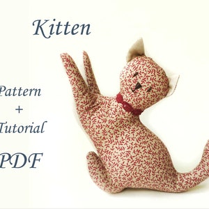 Puede incluir: Un gatito de tela rojo y blanco con un lazo rojo. La imagen incluye el texto "Kitten Pattern + Tutorial PDF".