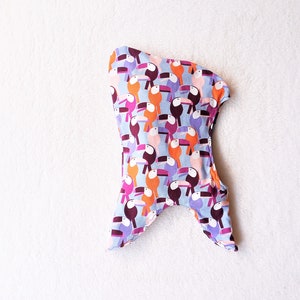 May include: A blue fabric pouch with a pattern of colourful toucans. The pouch is shaped like a fish with a pointed tail and a rounded head.