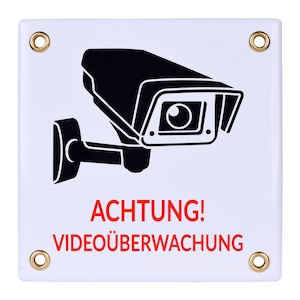 May include: White sign with black and white silhouette of a security camera and the text "ACHTUNG! VIDEOÜBERWACHUNG" in red.