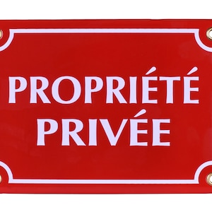 Op de afbeelding: Rood metalen bord met een witte rand en witte tekst die "PROPRIÉTÉ PRIVÉE" luidt.