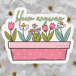 May include: A sticker featuring a pink flower pot with white polka dots, holding various flowers. The flowers include pink tulips, white daisies, and small pink flowers. The text "bloom anyway" is written above the flowers in green.