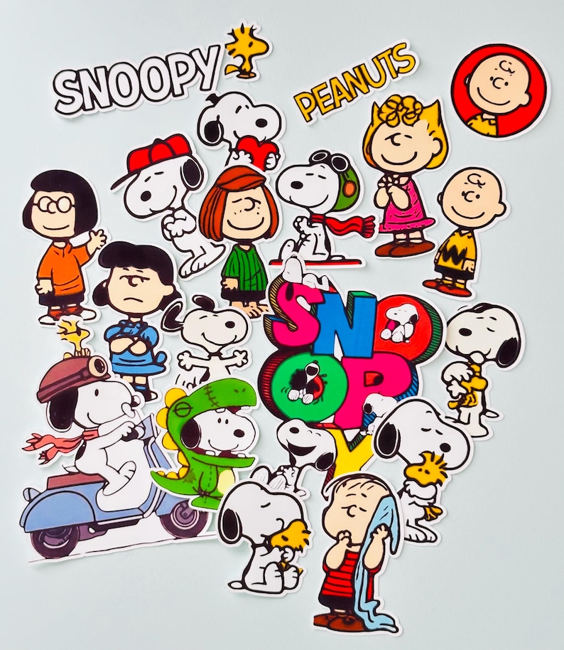May include: A selection of colourful Snoopy and Peanuts character stickers. The stickers feature Snoopy in various poses, along with Charlie Brown, Lucy, Linus, and other characters. The words "Snoopy" and "Peanuts" are also displayed.