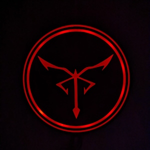 May include: A glowing red circular emblem against a black background. The emblem features a stylized design with a central vertical element and outward-pointing shapes, all in a vibrant red hue. The design is enclosed within a double red circle.