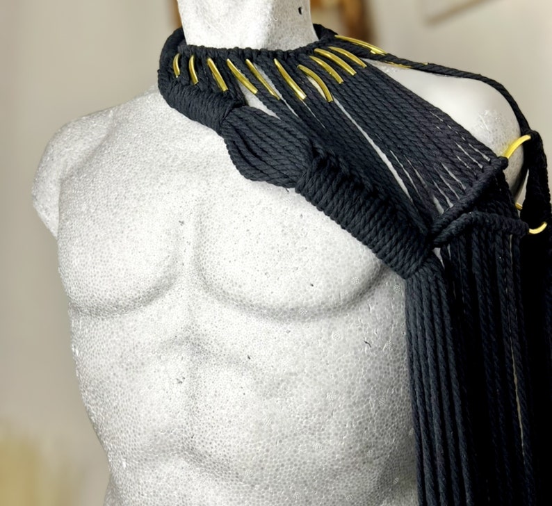 Peut inclure: Un collier en macram&eacute; noir avec des accents dor&eacute;s. Le collier est fait d'un cordon noir &eacute;pais et a un design en frange. Les accents dor&eacute;s sont de petits morceaux de m&eacute;tal ronds.