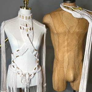 Peut inclure: Deux hauts en macram&eacute; blancs avec des accents dor&eacute;s. Un haut est de style halter avec un bas &agrave; franges. L'autre haut est un collier avec une longue frange.