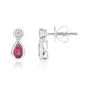 May include: A pair of silver-toned drop earrings featuring a round, clear, bezel-set stone at the top and a pear-shaped, deep pink gemstone suspended below. The earrings include a post back mechanism with a butterfly clutch for secure fastening.