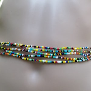 May include: Multicolored beaded waist beads with a mix of yellow, red, blue, green, black, and white beads.