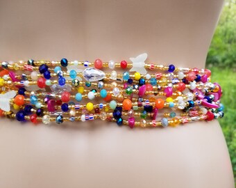 Puede incluir: Una cadena de cintura de cuentas de colores con múltiples hileras de cuentas en varios colores, incluyendo dorado, rojo, azul, verde y naranja. La cadena presenta pequeños abalorios de mariposa y cuentas de cristal.