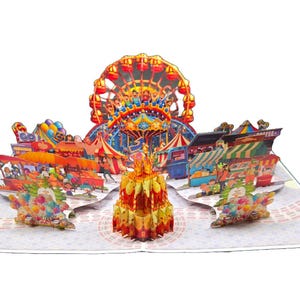 May include: A pop-up card depicting a colorful carnival scene. The card features a Ferris wheel, carousel, and various carnival booths. The card is open, revealing the 3D paper art with vibrant colors and intricate details.
