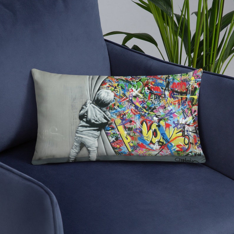 May include: A throw pillow featuring a colorful graffiti design with the word "LOVE" prominently displayed. A child peeks around a corner, revealing the graffiti behind a white wall.