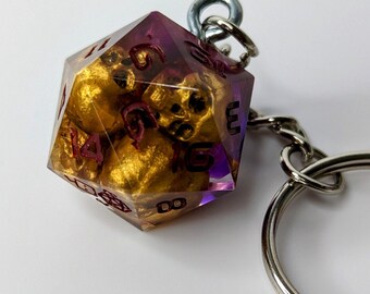 May include: A purple and gold dice keychain with a silver key ring. The dice has numbers 1 through 6 on each side.