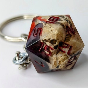 May include: A red and black skull-themed dice keychain with the numbers 1, 5, 7, 10, 12, and 20 visible.