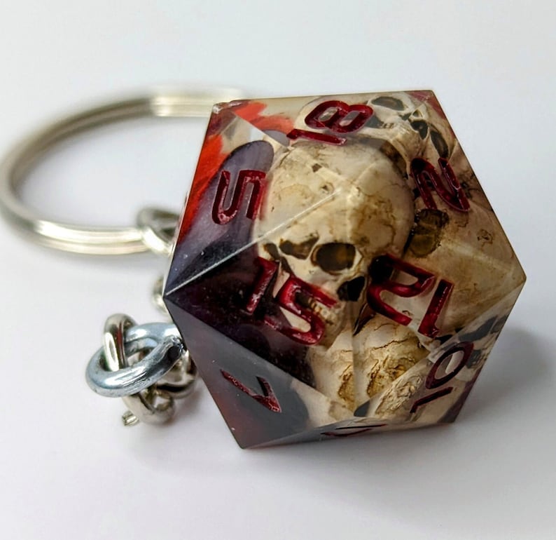 May include: A red and black skull-themed dice keychain with the numbers 1, 5, 7, 10, 12, and 20 visible.