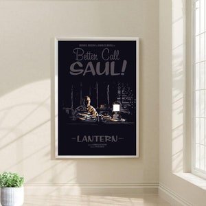 May include: A black and white poster with the title "Better Call Saul!" in a stylized font. The poster features a man sitting at a desk with a lamp on the desk. The poster is framed in a white frame.