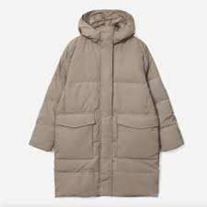May include: A long, tan puffer coat with a hood and two large front pockets. The coat is designed with a quilted pattern and a full-length zipper. The sleeves are long, and the coat appears to be made of a soft, insulated material.