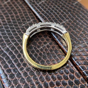 May include: A gold and silver band ring with a row of small diamonds set in a channel setting.