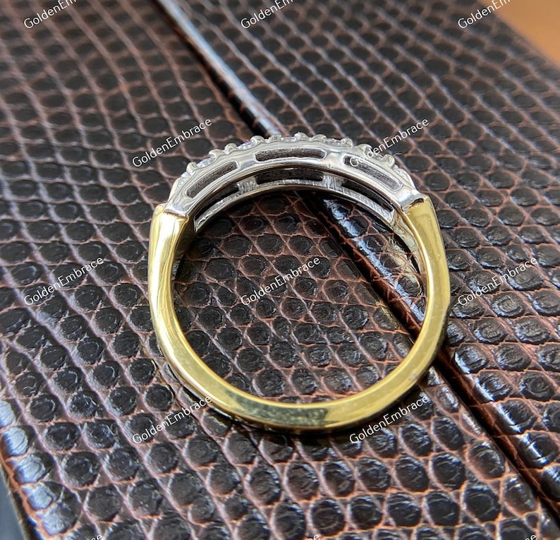 May include: A gold and silver band ring with a row of small diamonds set in a channel setting.