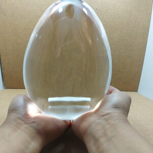 Pode incluir: Uma grande bola de cristal transparente de forma oval, segurada em duas m&atilde;os.