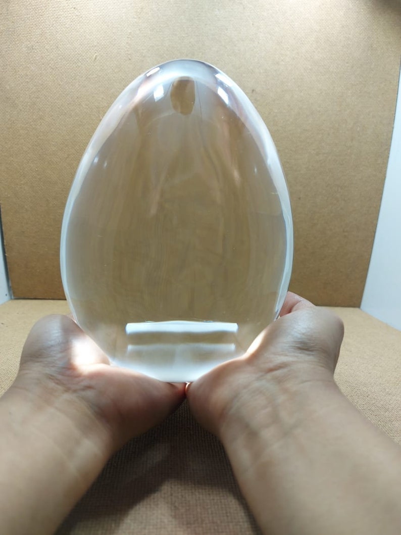 Pode incluir: Uma grande bola de cristal transparente de forma oval, segurada em duas m&atilde;os.