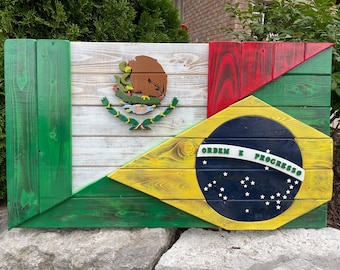 Op de afbeelding: Een houten bord met de vlaggen van Mexico en Brazilië. De Mexicaanse vlag bevindt zich links en de Braziliaanse vlag rechts. De vlaggen zijn gemaakt van hout en geschilderd in de kleuren van hun respectieve vlaggen. De Mexicaanse vlag heeft een kleurenschema van groen, wit en rood met het nationale wapen in het midden. De Braziliaanse vlag heeft een kleurenschema van groen, geel, blauw en wit met een gele ruit in het midden. De ruit bevat een blauwe cirkel met witte sterren en de tekst "ORDEM E PROGRESSO" in witte letters.