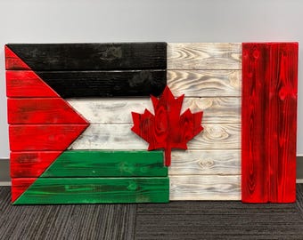 Op de afbeelding: Een houten vlag met de Palestijnse vlag links, de Canadese vlag in het midden en de Canadese vlag rechts. De vlaggen zijn gemaakt van houten planken die in de kleuren van elke vlag zijn geverfd.