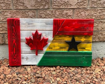 Op de afbeelding: Een houten vlag met de Canadese vlag aan de linkerkant en de Ghanese vlag aan de rechterkant. De vlaggen zijn geschilderd op gerecycled hout.