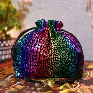 May include: A rainbow-coloured dice bag with a black background and a drawstring closure. The bag is made of a sparkly fabric with a polka dot pattern.