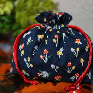 May include: A small blue drawstring bag with a red drawstring and a white and yellow mushroom pattern.